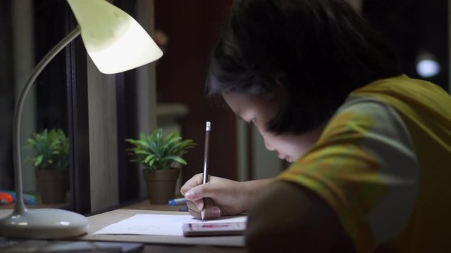 Asian children writting  and doing homework at home.Elementary happy Kid learning and reading book for study to the exam.Education concept.