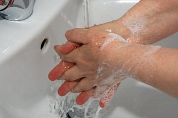 Washing hands by alcohol sanitizers or alcohol gel from pump bottle in public area.