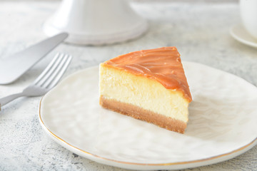 Plate with piece of tasty cheesecake on table