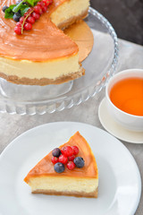 Plate with piece of tasty cheesecake and tea on table