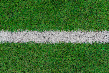 White stripe on the green soccer field top view. White line on artificial football field
