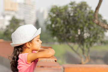 Little girl watching the sunset from a wall