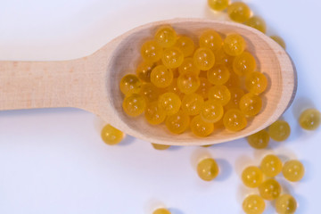 Fish oil. Cod liver oil omega 3 gel capsules. Granules in wooden spoon on white background.