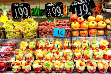 Pieces of different fresh fruits in plastic glasses in the Boqueria market, Barcelona, Spain