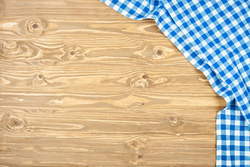 Blue checkered tablecloth on wooden table. Background with copy space. Horizontal. Top view.