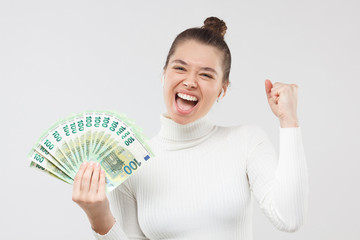 Fototapeta Excited happy young woman holding lots of money, fan of hundred euro banknotes in cash, shouting ot loud. Lottery winner concept. obraz