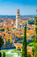 Fototapeta premium Vertical view of Verona historical city centre, Ponte Pietra bridge across Adige river, tower of Verona Cathedral, Duomo di Verona, red tiled roofs buildings, Veneto Region, Italy. Verona cityscape