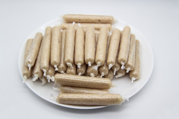 Fragrant fresh sausages made from chicken meat at home non-GMO on the plate. Ukrainian tasty food.  Raw handmade sausages on the plate. Many chicken sausages on the plate against white background