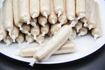 Fragrant fresh sausages made from chicken meat at home non-GMO on the plate. Ukrainian tasty food.  Raw handmade sausages on the plate. Many chicken sausages on the plate against dark background