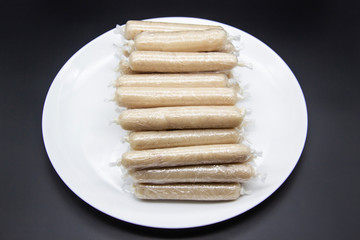 Fragrant fresh sausages made from chicken meat at home non-GMO on the plate. Ukrainian tasty food.  Raw handmade sausages on the plate. Many chicken sausages on the plate against dark background