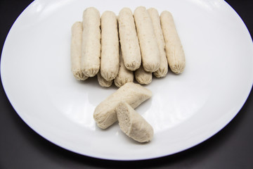 Fragrant fresh sausages made from chicken meat at home non-GMO on the plate. Ukrainian tasty food. Boiled handmade sausages on the plate. Many chicken sausages on the plate against background