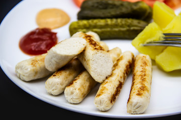 Delicious homemade chicken sausages boiled and made on the fire. Fragrant sausages made from non-GMO chicken. Toasted Mini Sausages from chicken on the plate