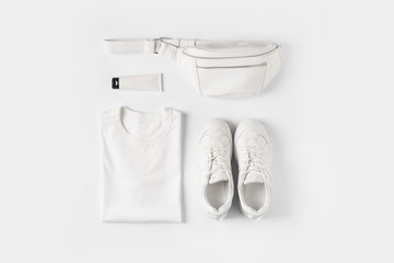 Fashion flat lay with white t shirt, sneakers, waist bag and accessories, monochrome concept,...
