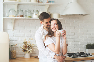 Lifestyle consept at home with couple young men and woman  with cup of coffee or tea in kitchen