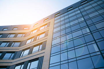 Facade of modern glass building at sunset. Warm and cool tone contrast. Sun flare.