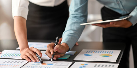 Cropped image of data analyst team working together with computer tablet and graphic charts...
