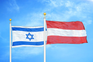 Israel and Austria two flags on flagpoles and blue cloudy sky