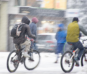 Cyclists on the city roadway in snowy day in motion blur