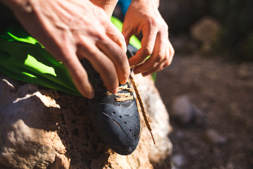 Rock climber puts on climbing shoes and ties shoelaces.