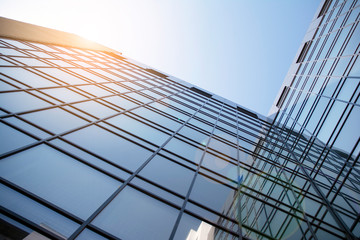 Facade of modern glass building at sunset. Warm and cool tone contrast. Sun flare.