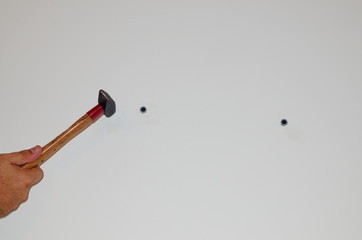 Hammering plastic screw anchor plugs into a concrete wall