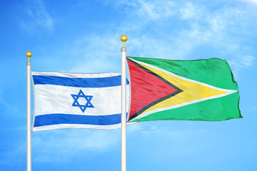 Israel and Guyana two flags on flagpoles and blue cloudy sky