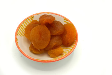 Dried apricots on a ceramic saucer isolated on white background. Energy and fiber natural source. Dieting food.