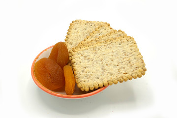 Dried fruits and digestive biscuits on a ceramic saucer isolated on white background. Energy and fiber natural source. Dieting food.