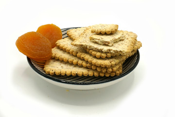 Dried fruits and digestive biscuits on a ceramic saucer isolated on white background. Energy and fiber natural source. Dieting food.