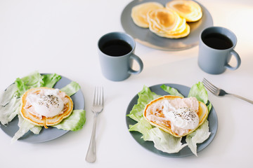 Healthy nutritious tasty breakfast. Pancakes, poached egg on ceramic plate and coffee cup. table setting. food photo. good morning