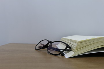 Education concept. Learning concept with opening book or textbook. Back to school concept. Book and glasses on wooden table. Reading glasses and a book on white background. 