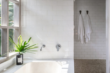 White bathroom interior, built bathtub, vase on top near wooden window frame
