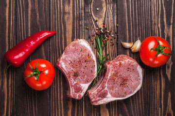  Pork steak with spices, vegetables and rosemary. Juicy and fresh raw meat, tomatoes, paprika,...