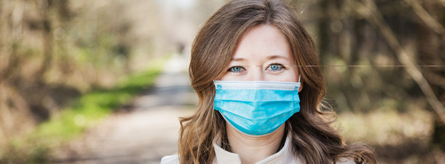 Frau mit Atemschutzmaske beim spaziergang im Park. Corona Virus Schutz.