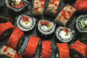 Various kinds of sushi served on dark plate macro