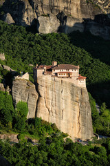 Fototapeta na wymiar Monastery of Rousanou perched on a cliff in famous greek tourist destination Meteora in Greece on sunset with scenic landscape