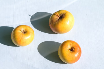 view from above yellow apple with a hard sunlight and deep shadow on a table, zero waste still life and healthy food concept, empty space for text