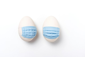 Zwei Ostereier mit Mundschutz auf weißem Hintergrund