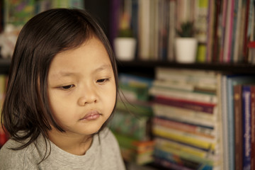 Young Asian girl with bookshelf in background