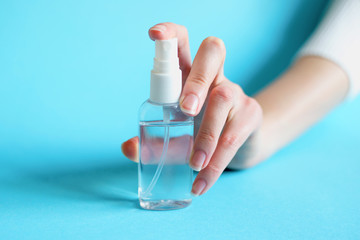 Female hand holds a bottle of sanitizer gel, antibacterial alcohol spray from coronavirus bacteria isolated over blue background, covid 19, hand hygiene