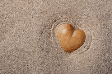 Stone heart in the sand. Vibrating waves on the sand from a beating heart