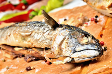 Smoked mackerel with garlic, pepper and coarse salt on baking paper.