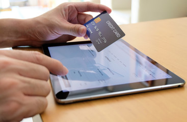 Men hand holding credit card and type payment information on tablet device for order online shopping. Internet technology and Digital market place E-Commerce lifestyle concept, Purchase transaction.