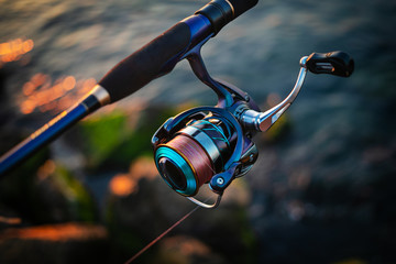 Fishing reel and rod, blurred background.