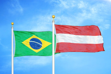 Brazil and Austria two flags on flagpoles and blue cloudy sky