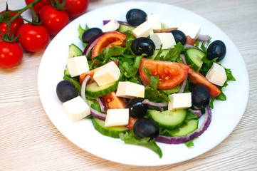Greek salad with tomatoes, cucumbers and feta cheese with olives on the table