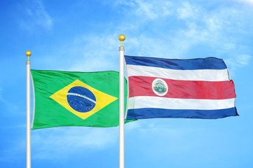 Brazil and Costa Rica two flags on flagpoles and blue cloudy sky