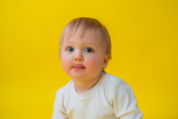 Healthy baby in white bodysuit sits on a yellow background, space for text