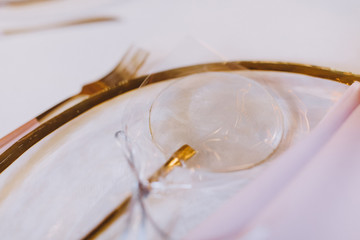 on a transparent glass plate lies a pink napkin, a personalized card in the form of a coral and a sweet lollipop on a stick