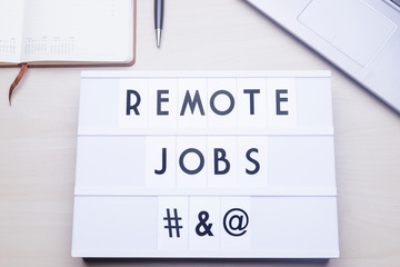 Workspace table with a lichtbox with the words REMOTE JOBS.